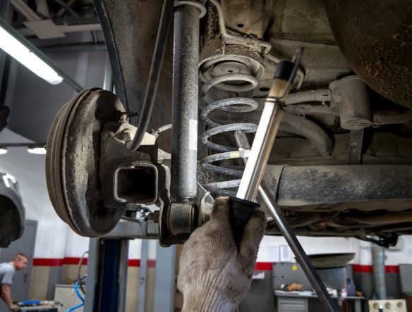 mechanic holding a light close to car shocks
