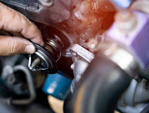 mechanic removing thermostat from car