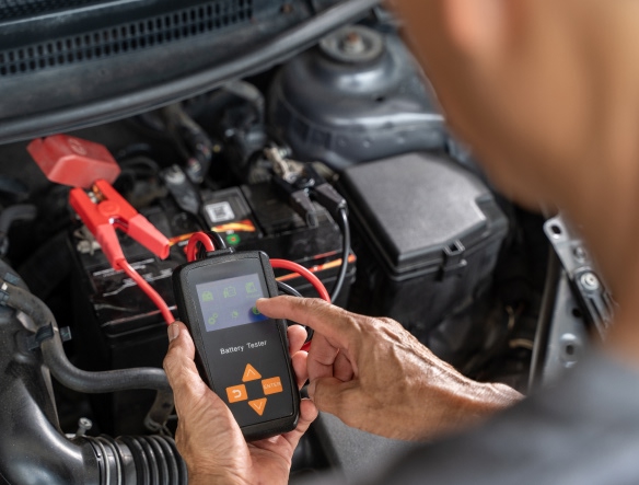 mechanic using a battery tester